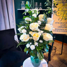 White roses and carnations in a teal glass vase