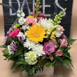 Mixed bouquet with a yellow gerbera daisy, pink roses, and white daisies in a box