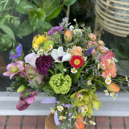 Mixed bouquet with roses, daisies, and orchids in a glass vase