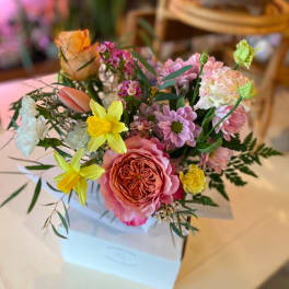 Mixed bouquet of pink, yellow, and white flowers in a white box