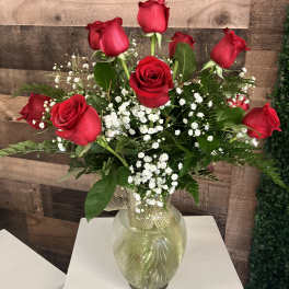 Red roses arranged in a clear glass vase with white baby's breath