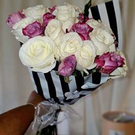 Bouquet of white and pink roses wrapped in black-and-white striped paper