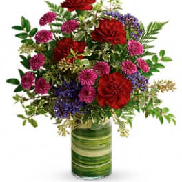 Mixed red and purple flowers in a green striped glass vase