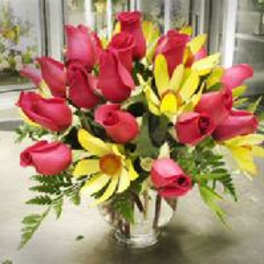 Bouquet of red roses and yellow daisies in a clear vase