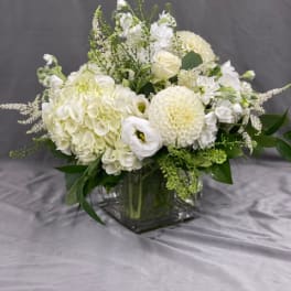 White floral arrangement in a square glass vase with round blooms
