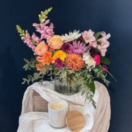 Mixed bouquet in a glass vase with a candle in front