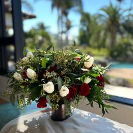 Red and white rose arrangement in a dark vase