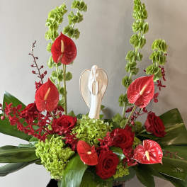 Red roses and anthuriums with green hydrangeas and a small angel figurine
