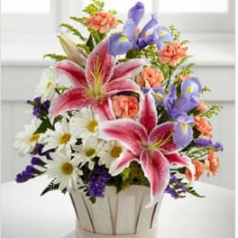 Bouquet of pink lilies, purple irises, and white daisies in a wooden basket