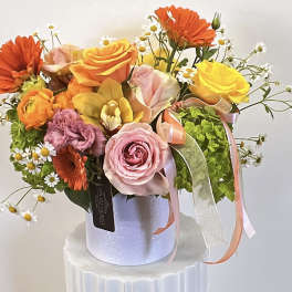 Bouquet of roses, gerbera daisies, and small white daisies in a white hatbox