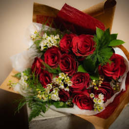 Bouquet of red roses with white filler flowers wrapped in brown and red paper