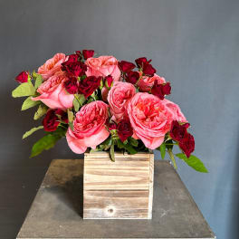 Pink and red roses arranged in a wooden box