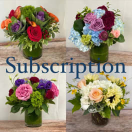Four colorful flower arrangements in glass vases on a wooden surface