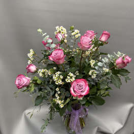 Pink roses arranged in a clear glass vase with small white filler flowers