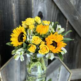 Yellow sunflowers and roses in a clear glass vase
