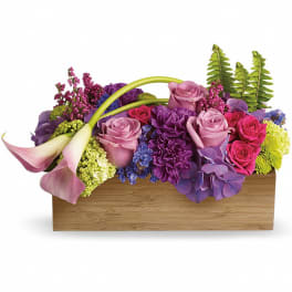 Colorful floral arrangement in a wooden box with pink calla lilies and roses