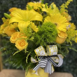 Yellow floral bouquet in a vase with striped ribbon