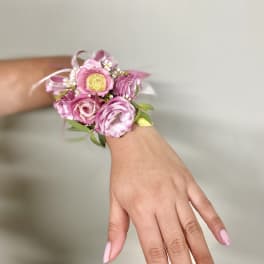 Pink floral wrist corsage with ribbon on a person's wrist