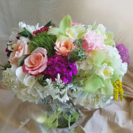 Bouquet of pink roses, white hydrangeas, and green orchids in a glass vase