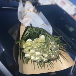 Bouquet of white roses wrapped in tan paper with white ribbon