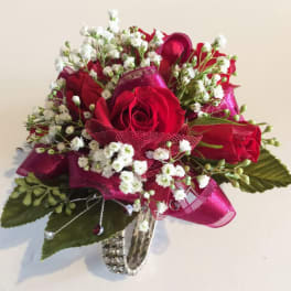 Red roses with white baby's breath and pink ribbon in a silver vase