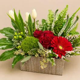 Red roses and a red gerbera daisy in a rectangular vase with white tulips