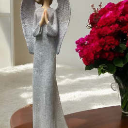 Angel figurine beside a vase of bright pink flowers