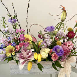 Mixed floral arrangement in a rectangular container with pink, purple, yellow, and white blooms
