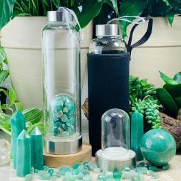 Two glass water bottles with metal caps and crystal stones beside green crystal decor.