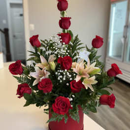 Red roses and pale lilies arranged in a red hatbox