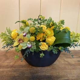 Yellow floral arrangement in a black bowl vase