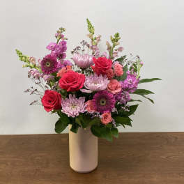 Mixed pink and purple flowers arranged in a white vase