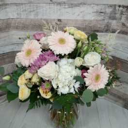 Mixed pastel bouquet in a glass vase with pink daisies and white roses