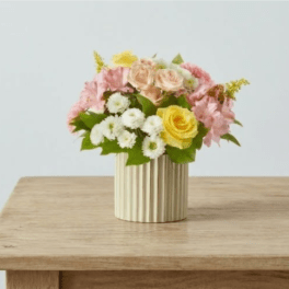 Pink and yellow flower arrangement in a ribbed vase