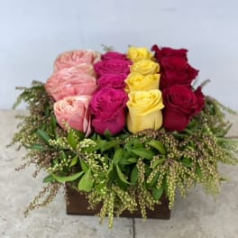 Box arrangement of pink, magenta, yellow, and red roses