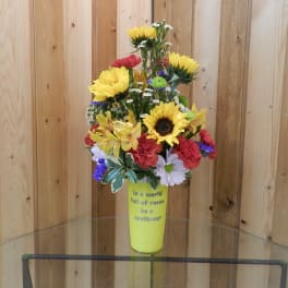 Mixed bouquet with sunflowers and carnations in a yellow vase