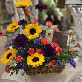 Basket arrangement with yellow sunflowers, purple carnations, and pink mini carnations