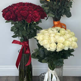 Three large rose bouquets in glass vases, in red, orange-yellow, and white