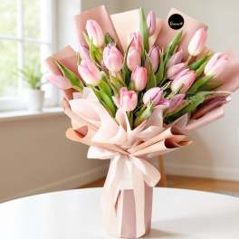 Bouquet of pink tulips wrapped in blush paper with a ribbon