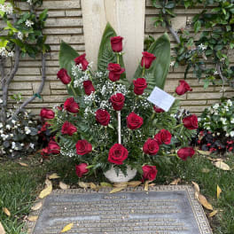 Red roses arranged in a white basket at a gravesite memorial