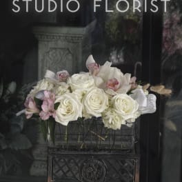 White roses and pink orchids arranged in a rectangular container
