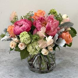 Mixed pink and peach flower arrangement in a clear glass vase