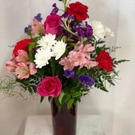 Mixed bouquet of pink, red, white, and purple flowers in a dark vase
