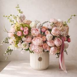 Large pastel bouquet of pink and white flowers in a ribbed white vase