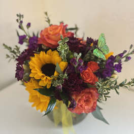 Bouquet of sunflowers, orange roses, and purple flowers in a vase