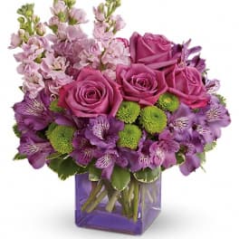 Purple roses and lavender flowers in a square glass vase