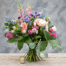 Mixed bouquet of pink, white, and blue flowers in a glass vase
