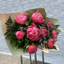 Bouquet of bright pink peonies wrapped in pastel paper