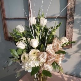 White tulips and cream flowers in a glass vase with striped ribbon