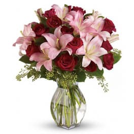 Pink lilies and red roses arranged in a clear glass vase